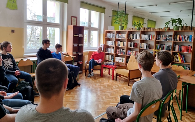 Krzysztof Kamiński z uczniami na tle książek w bibliotece szkolnej_zdjęcie zbiorowe