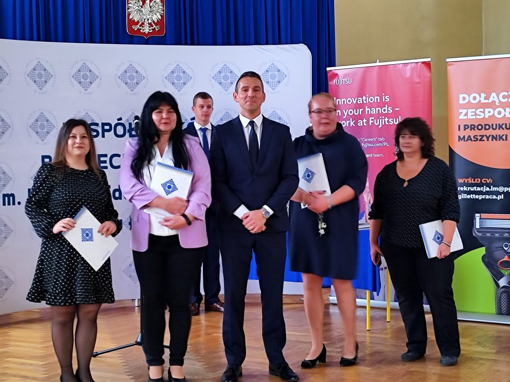 Nagrodzeni pracownicy administracji z dyrektorem na tle baneru ZSP w Łodzi