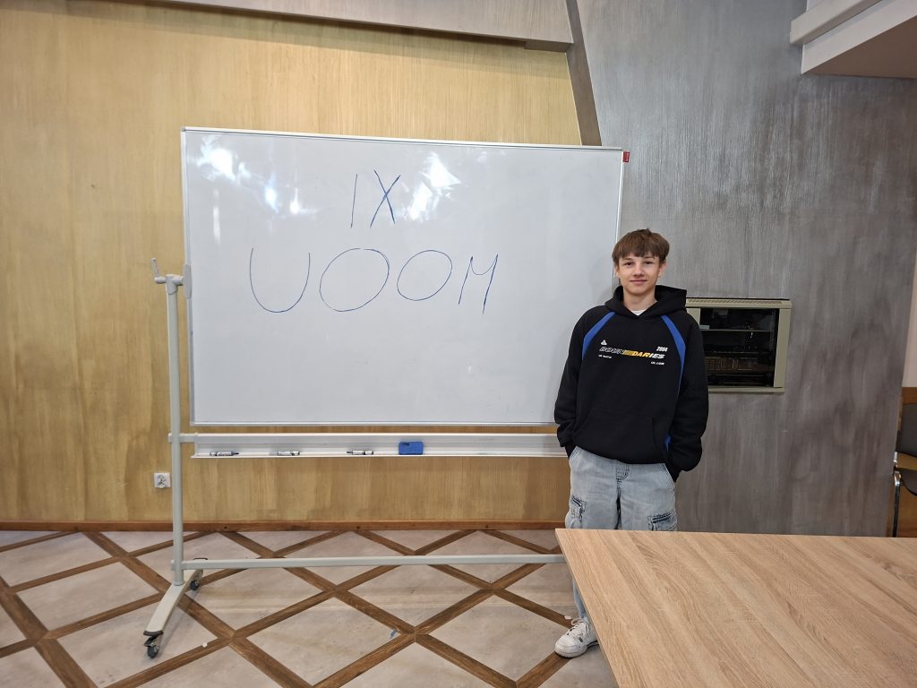 Uczeń przy tablicy z napisem IX UOOM