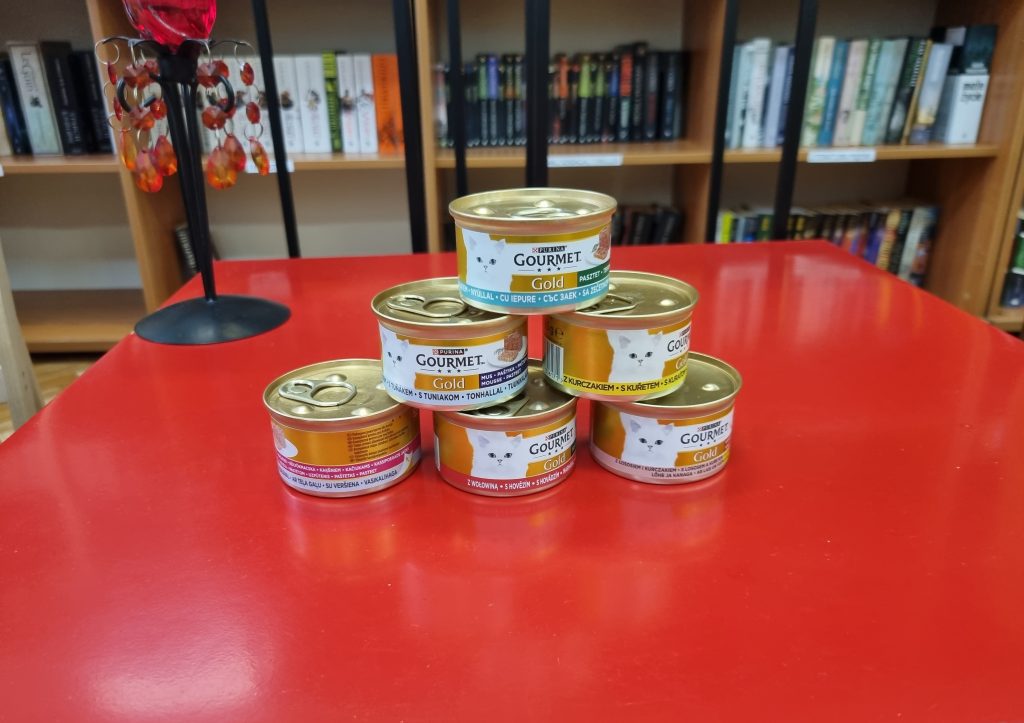 Na czerwonym stoliku puszki dla kota