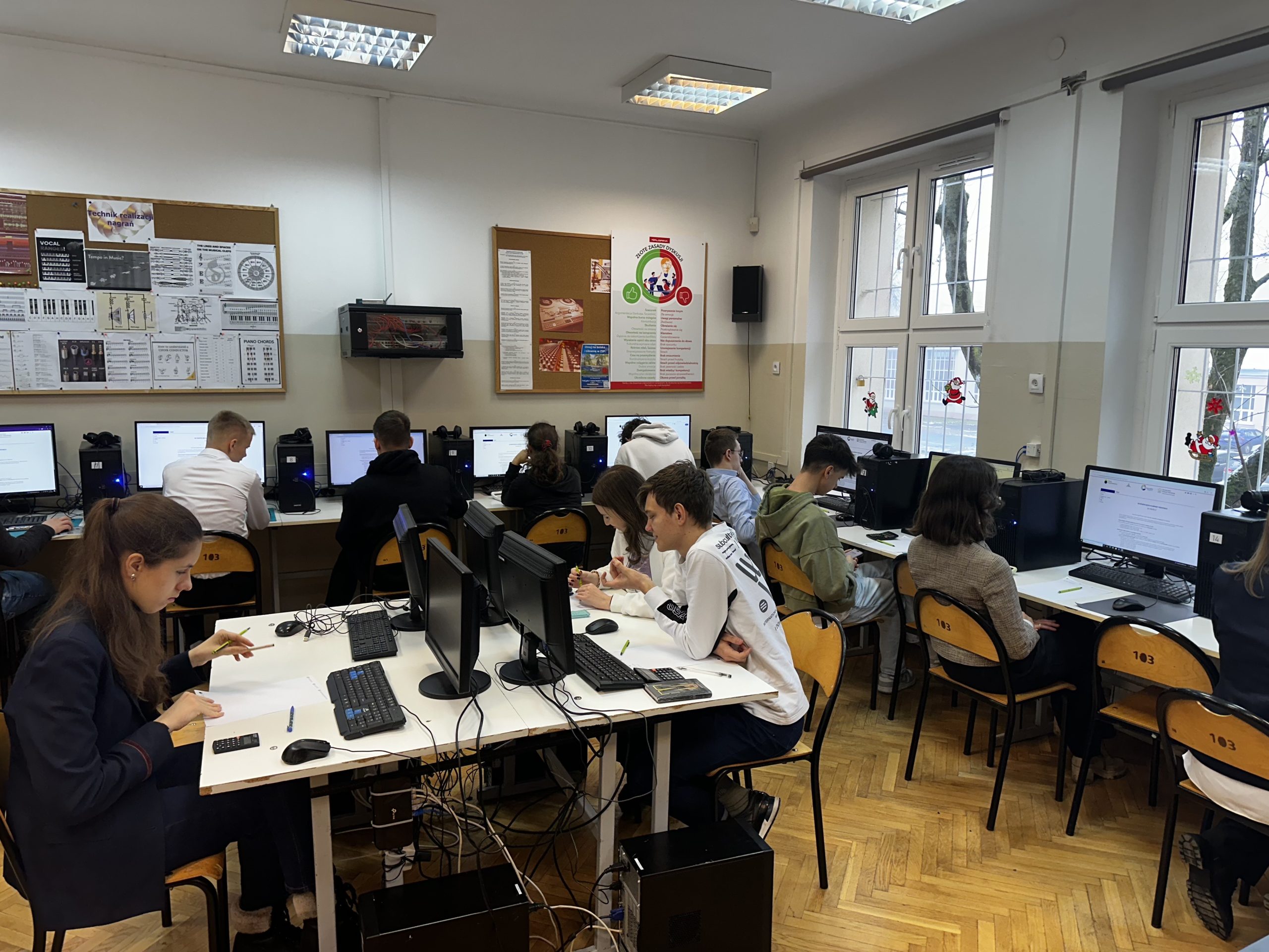 Uczestnicy Olimpiady Statystyczne siedzą przed ekranami komputerów.