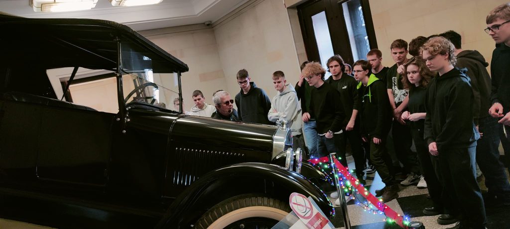 Grupa uczniów przy zabytkowym samochodzie